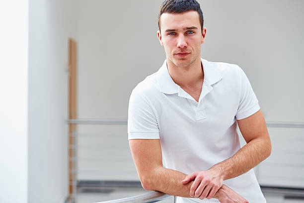 Man in a polo shirt stands leaning on railing