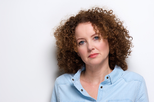 Close up portrait of an attractive older woman with curly hair posing against white background