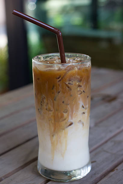 istock Iced coffee macchiato glass placed on a wooden panel table 473946920