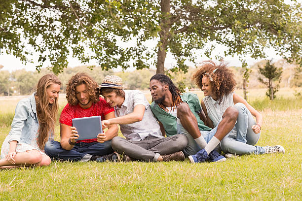 istock Happy friends in the park looking at tablet 473960678