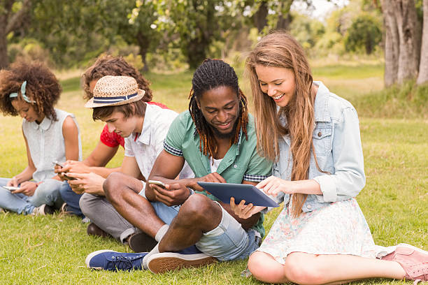 istock Happy friends in the park looking at tablet 473960702