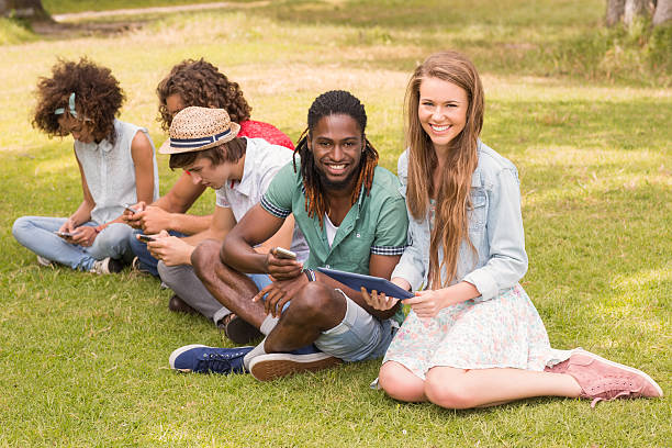 istock Happy friends in the park looking at tablet 473960704