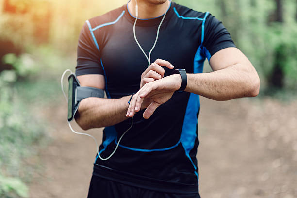 läufer im park vorbereitung zum joggen - gps watch stock-fotos und bilder