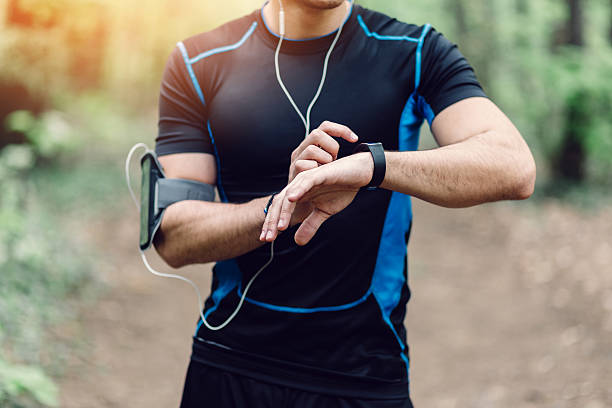 Runner in the park preparing for jogging Runner fixing time at sports smart watch checking sports stock pictures, royalty-free photos & images