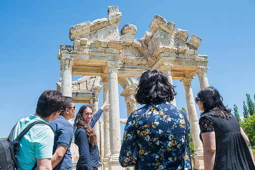 Guide explaining to tourists in front of the Tetrapylon in Aphrodisias, Turkey. The ancient city of Aphrodisias is one of the most important archaeological sites of the Greek and Roman periods in Turkey. Famous in antiquity for its sanctuary of Aphrodite, the city's patron goddess, Aphrodisias enjoyed a long and prosperous existence from the second century B.C. through the sixth century A.D.  Today, many of the city's ancient monuments remain standing, and excavations have unearthed numerous fine marble statues and other artifacts. The great beauty and extraordinary preservation of this site combine to bring the civic culture of the Greco-Roman world vividly to life.
