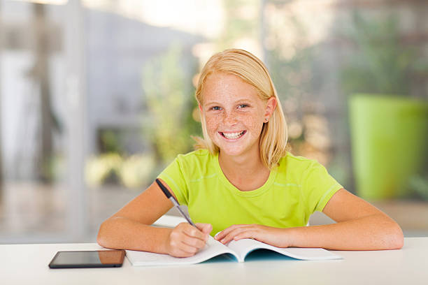 cute teen girl doing homework cute teen girl doing homework at home 12 13 years pre adolescent child female blond hair stock pictures, royalty-free photos & images