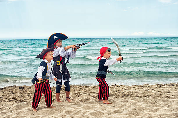 istock Kids wearing pirate costumes playing on the beach. 473997730