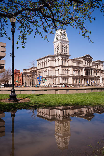 City Hall Building Downtown Louisville Kentucky Built 1871 City Hall is reflected in water that has collected in the park across the street during recent flooding city street street corner tree stock pictures, royalty-free photos & images