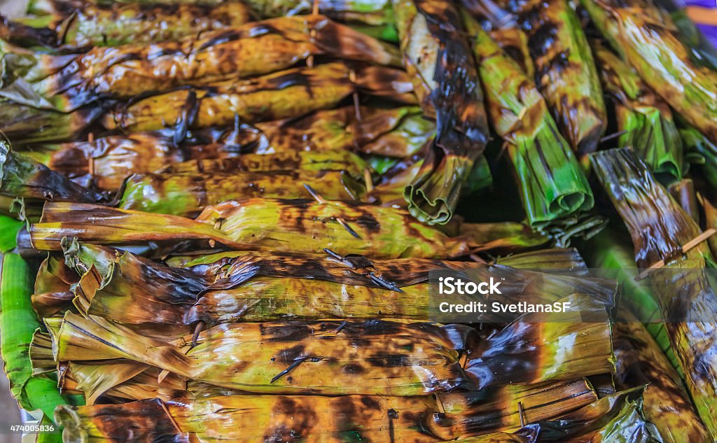 Fresh Produce at the market Thai dessert "ka-nom-sai-sa i"  wrapped in banana leaves with long coconut leaves tail 2015 Stock Photo