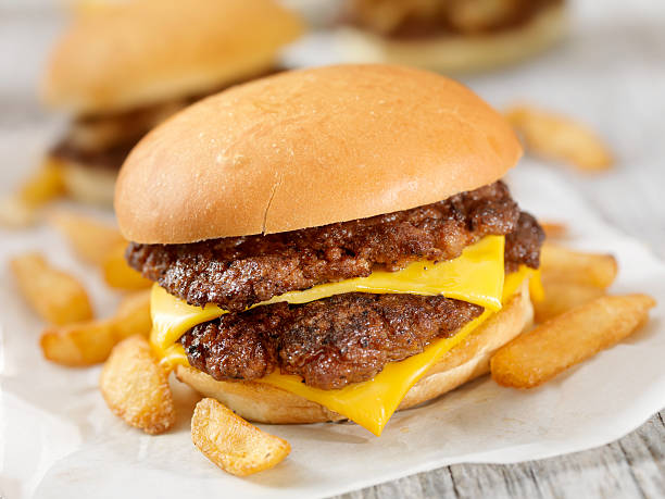 cheeseburger mit doppelbett - cheese focus on foreground on top of portion stock-fotos und bilder