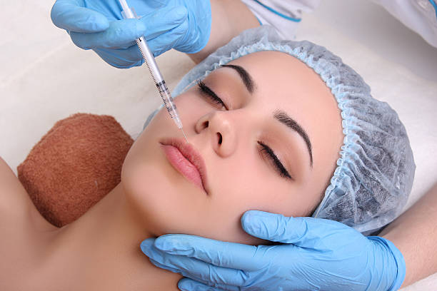 istock Beautiful woman gets an injection in her face. 474017818