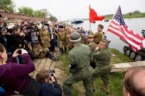 Torgau, Germany - April 25, 2015: Re-enactment of the historic fraternization of the russian and the american armies at the Elbe river in Torgau in 1945. American and russian soldiers in front of a large group of journalists. The 70th Elbe Day celebration is a commemoration for the victims of World War 2 and the russian and american armies that met at the Elbe river to end the war.