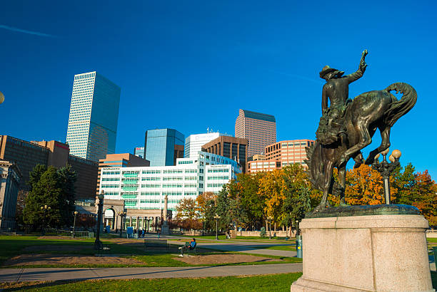 Denver, United States - October 26, 2008: The Denver skyline in the background with Civic Center Park, park visitors, and the Bucking Bronco statue in the foreground to the right.  Picture taken during Autumn.