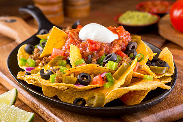 Nachos Supreme A plate of delicious tortilla nachos with melted cheese sauce, ground beef, jalapeno peppers, red onion, green onions, tomato, black olives, salsa, and sour cream with guacamole dip. potato chip photos stock pictures, royalty-free photos & images