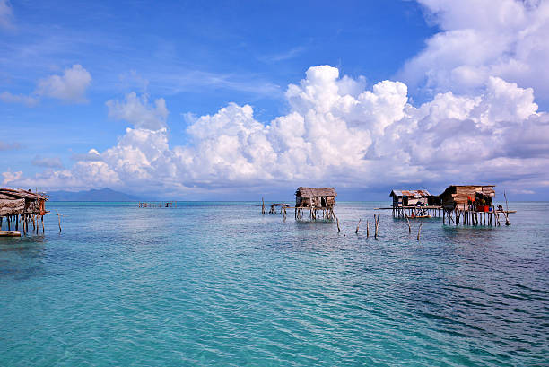 Borneo Floating Village Maiga Island, Sabah, Malaysia Borneo's sea gypsy stilt houses reflected in water on Maiga Island, Sabah Borneo, Malaysia. view into land stock pictures, royalty-free photos & images