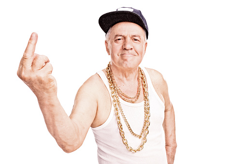 Senior man with a hip-hop cap and a golden chain, giving the finger and looking at the camera isolated on white background
