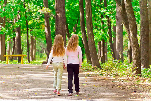 istock Cute two girls walking in park 474068716