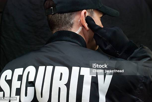 Security Guard Listens To Earpiece Back Of Jacket Showing Stock Photo - Download Image Now