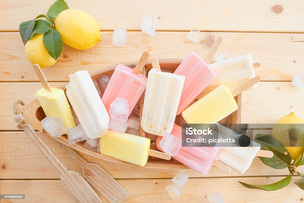 Variety of frozen fruit Popsicles on a wooden surface Variety of frozen fruit popsicles in little wooden boat 2015 Stock Photo