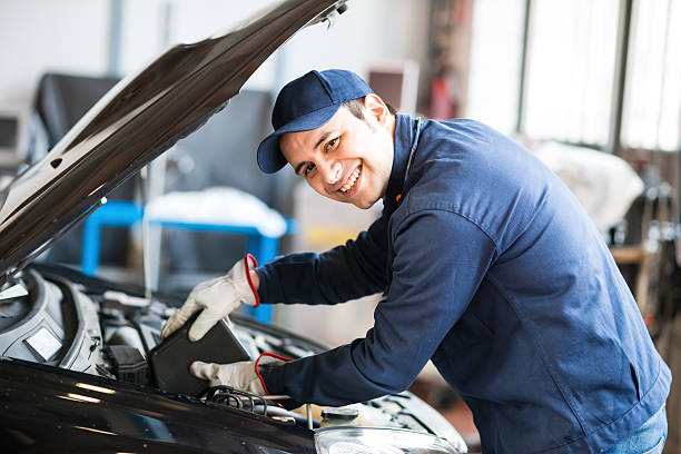 Auto mechanic putting oil in a car engine stock photo