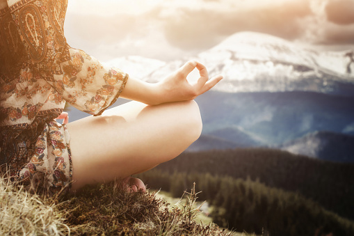 Young woman meditating in cloudy mountains