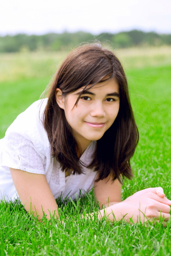 Beautiful biracial teen girl relaxing on lush green grass