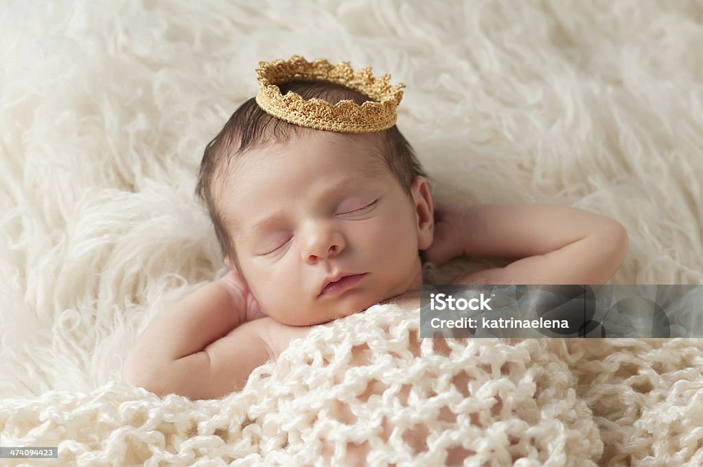 Newborn Baby with Prince's Crown Portrait of a 12 day old newborn baby boy wearing a gold crown. He is sleeping on a beige flokati rug with his hands behind his head. Baby - Human Age Stock Photo