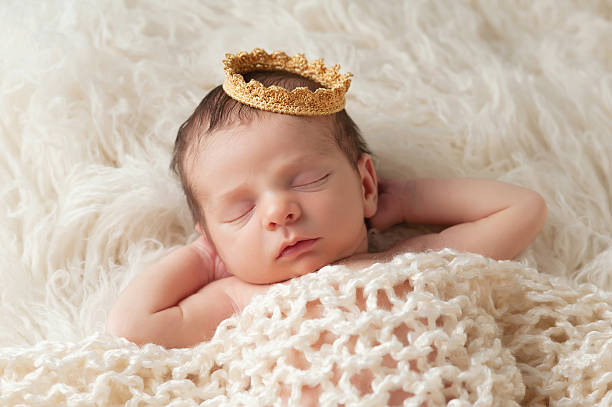 Newborn Baby with Prince's Crown Portrait of a 12 day old newborn baby boy wearing a gold crown. He is sleeping on a beige flokati rug with his hands behind his head. baby boys photos stock pictures, royalty-free photos & images