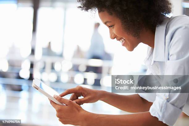 Smiling Young Woman In An Office Using A Tablet Stock Photo - Download Image Now - 20-29 Years, 2015, Adult