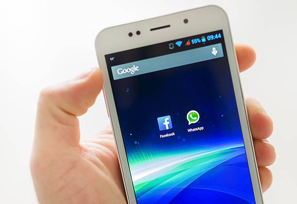 Florence, Italy - February 20, 2014: Close up view of an hand holding an android smartphone (Brondi Gladiator 2) with the app Facebook and WhatsApp on the screen. 4 inch display. Studio shoot. Whatsapp and facebook are both social networking app to communicate without any cost.