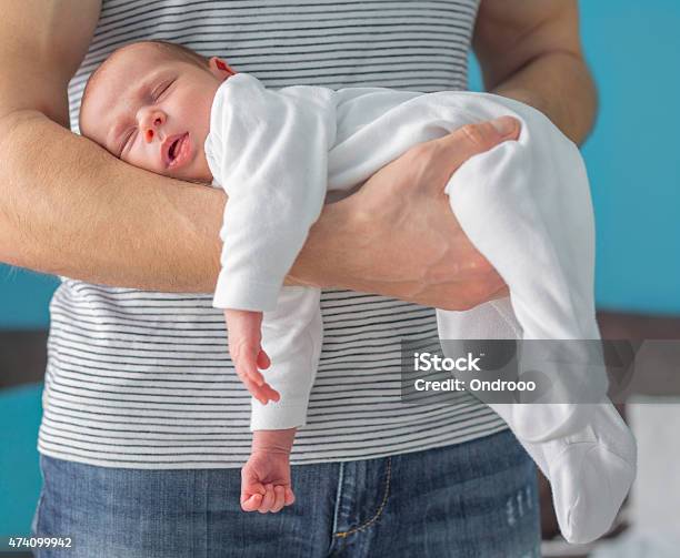 A One Month Old Baby Is Asleep In An Arm Of A Standing Man Stock Photo - Download Image Now