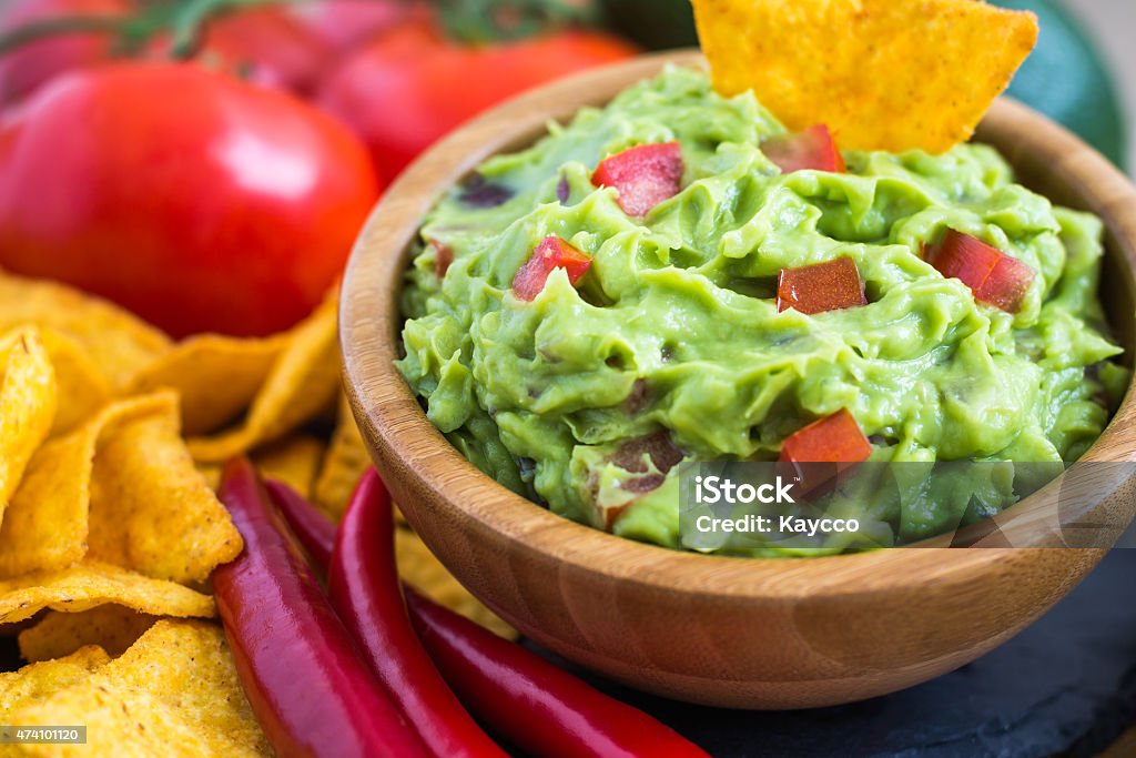 Guacamole made from fresh ingredients Guacamole in Wooden Bowl with Tortilla Chips and Ingredients 2015 Stock Photo