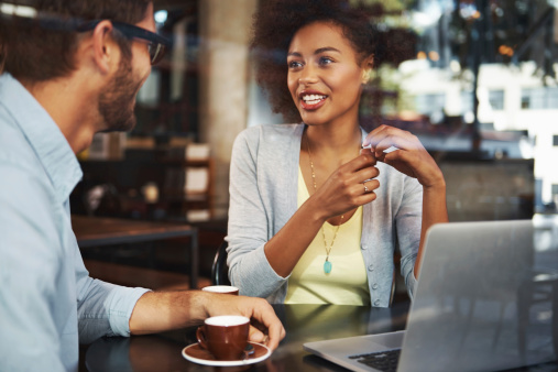 Shot of two people having a coffee at a coffee shop with a laptop in front of them