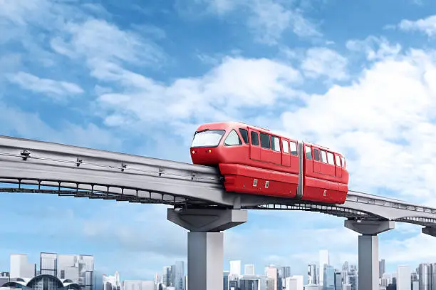 Red monorail train against blue sky and modern city in background