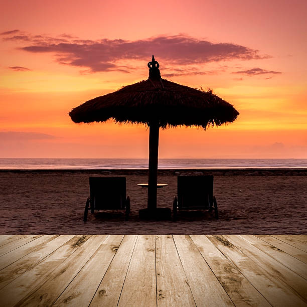istock Empty wooden platform facing a sunrise with beach umbrella 474106032