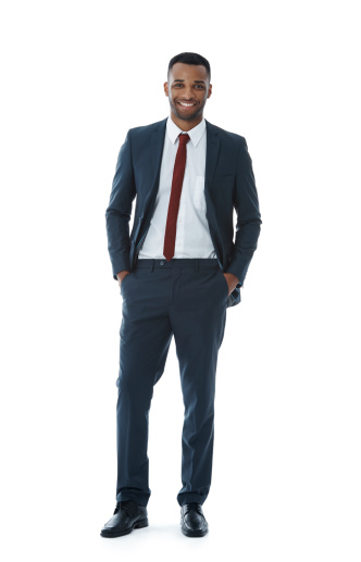 A smiling businessman standing with his hands in his pockets while isolated on white