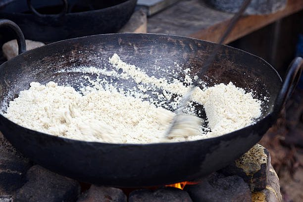 Camel herder roasting coconut in pan over open wood fire