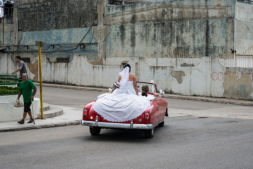 Havana, Cuba - December 16, 2014: A bride rides in the back of a vintage convertible through the streets of Regla, a district of Havana, Cuba