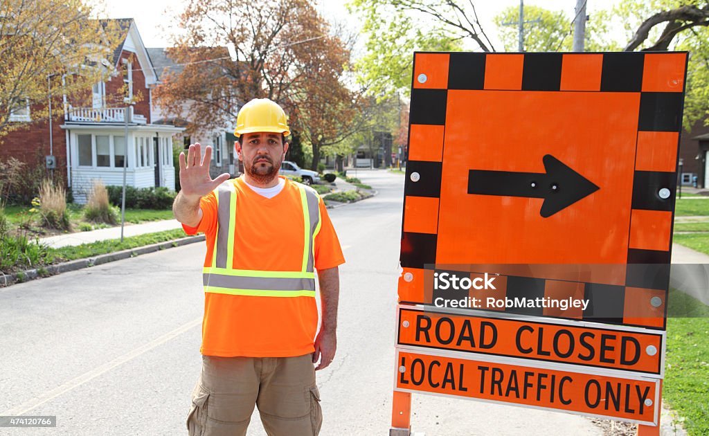 Road Closed - Local Traffic Only A construction worker puts up his hand to indicate that the road is closed and only local traffic may proceed. Gesturing Stock Photo