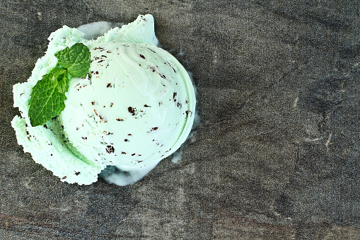 Scoop of delicious chocolate chip mint ice cream with mint leaves.