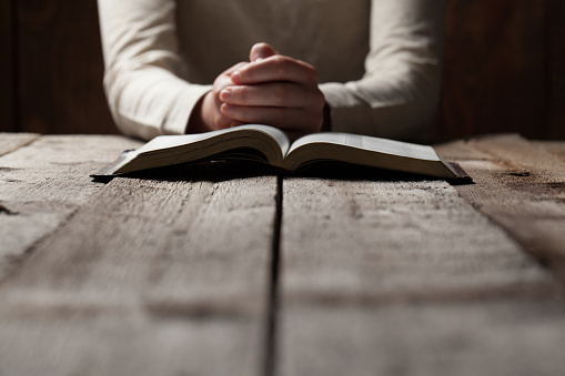woman finger presses on bible book over wooden background