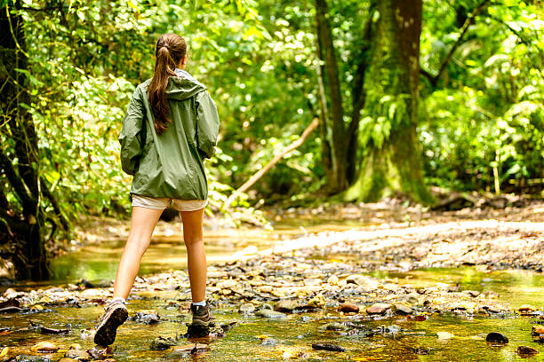 istock Young woman hiking on a tropical rainforest river, 474139601