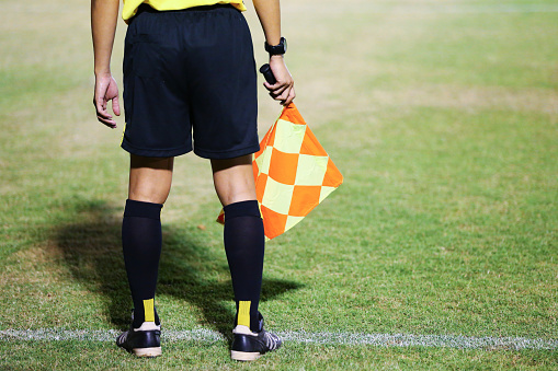 Assistant referees signalling with the flag on the sideline during a soccer match