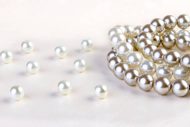 istock Silver and white pearls necklace on white paper 474143694