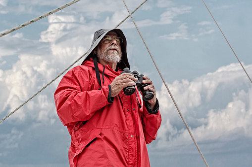 A man on the bow of a sailboat overlooks checking the seas and the weather.