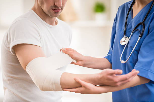 At doctor's Close-up of female doctor with stethoscope  bandaging hand of male patient. wounded stock pictures, royalty-free photos & images