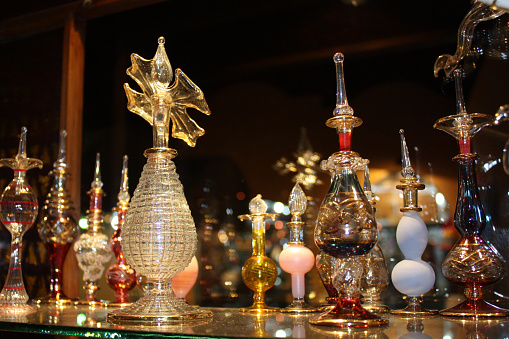 Several Arabian perfume flasks are arranged on a glass shelf in front of a mirror.