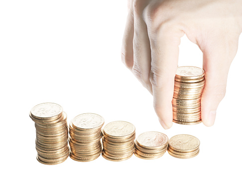 Group of stack of one dollar coins in descending order from left to right isolated on white with hand giving additional stack of dollar coins. A representation of helping hand.