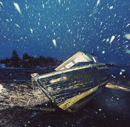 An abandoned fishing boat rests on the shores of the Atlantic during a snowstorm.  Long exposure.