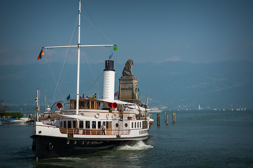 Lindau, Germany - May 16, 2015: See the famous lighthouse and the Bavarian Lion protecting the harbour entry. A steamboat is arriving. Captain is on board and manages the arrival